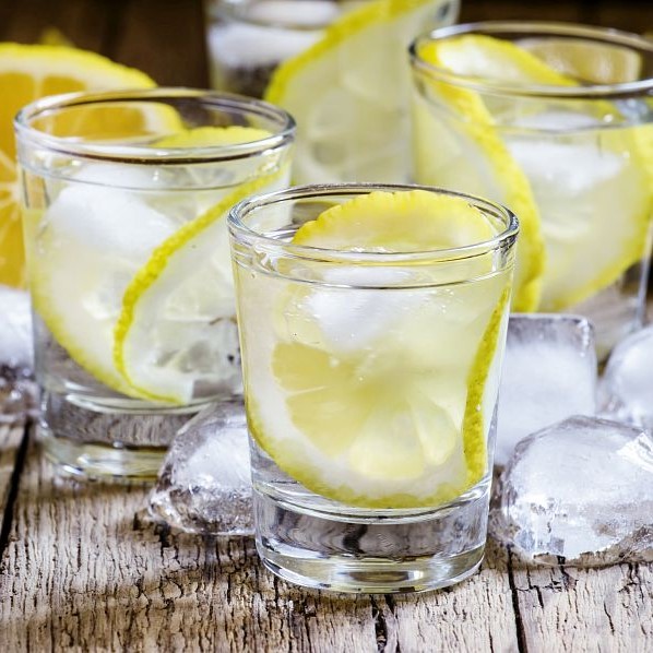 Lemon vodka with ice, vintage wooden background, selective focus