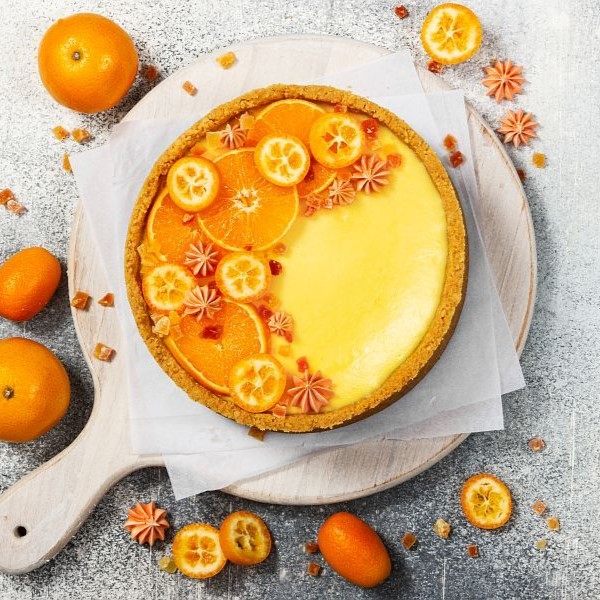 Cheesecake with slices of orange and kumquat on a gray stone