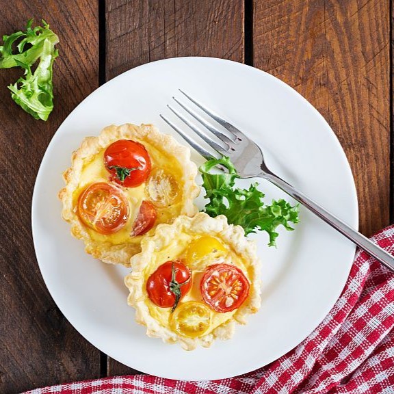 Cheddar, tomatoes tartlets on wooden background. Mini pies. Delicious appetizer, tapas, snack. Top view. Flat lay