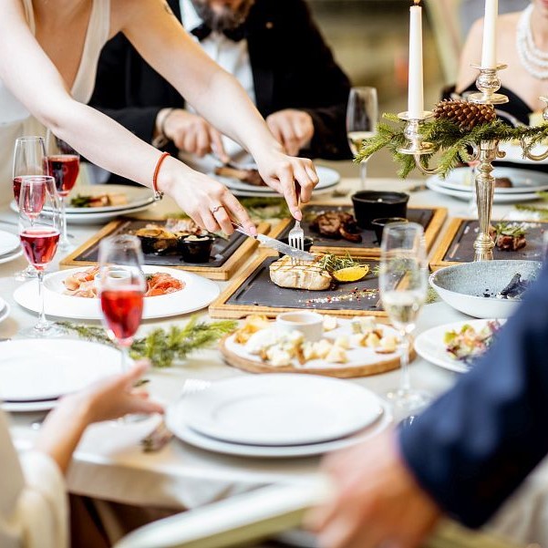 People having a festive dinner at a well-served table with tasty dishes during New Year Eve at the luxury restaurant, close-up view with no face