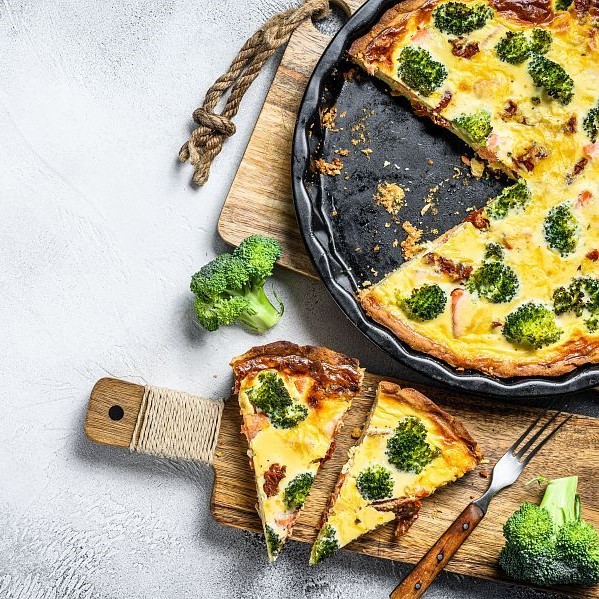 Homemade quiche tart with red fish and broccoli. White background. Top view. Copy space